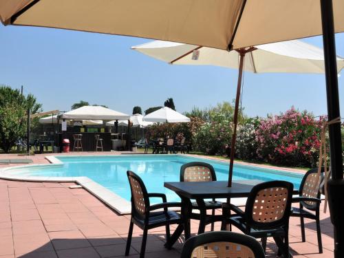 een tafel met stoelen en een parasol naast een zwembad bij Agriturismo La Prosciutta in Faenza