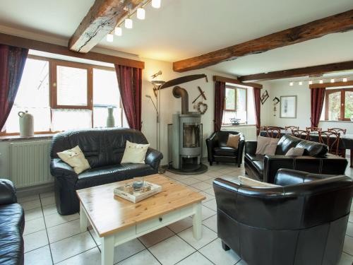 a living room with leather furniture and a wood stove at Spacious Holiday Home in Humain with Garden in Marche-en-Famenne