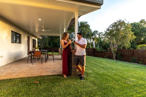 a man and a woman standing outside of a house at Birds 'n' Bloom Cottages in Yungaburra