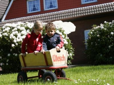 dos niños jugando en un tren de juguete en un patio en Utesch's Ferienwohnungen, en Neuharlingersiel