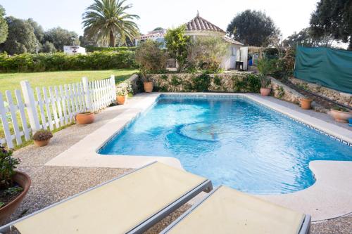 einen Pool in einem Garten mit einem weißen Zaun in der Unterkunft Orquideas in Cala Galdana