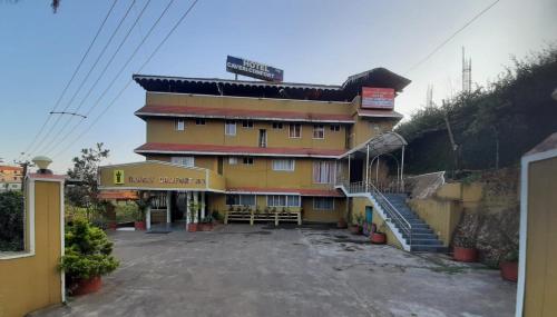 un grand bâtiment jaune avec des escaliers en face de celui-ci dans l'établissement HOTEL CAVERI COMFORT INN, à Madikeri