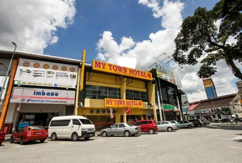 una strada cittadina con auto parcheggiate di fronte a un hotel di My Town Hotel a Ipoh