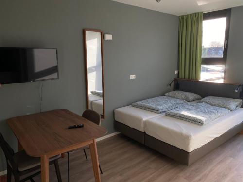 Schlafzimmer mit einem Bett, einem Tisch und einem TV in der Unterkunft Short Stay Wageningen in Wageningen