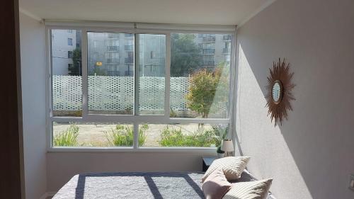 1 dormitorio con ventana y vistas a un edificio en Hermoso departamento con piscina, muy cerca del centro, playas, malls, hipermercado, hospital y clínicas, en La Serena