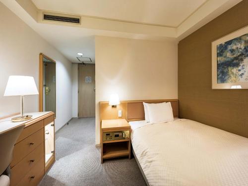 una camera con letto e scrivania con lampada di Utsunomiya Tobu Hotel Grande a Utsunomiya