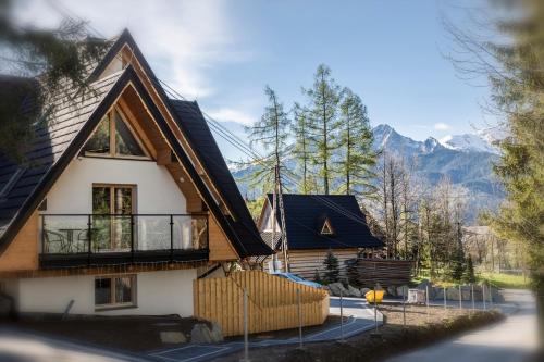 une maison avec un balcon et des montagnes en arrière-plan dans l'établissement TatryTop Apartamenty Alpejski SPA, à Kościelisko