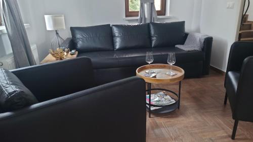 sala de estar con sofá negro y mesa con copas de vino en Mazurskie Siedlisko Langen, en Mrągowo