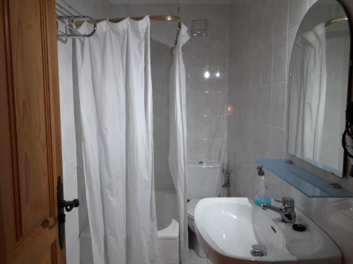 a bathroom with a white shower curtain and a sink at Apartamentos Fernando in Santillana del Mar