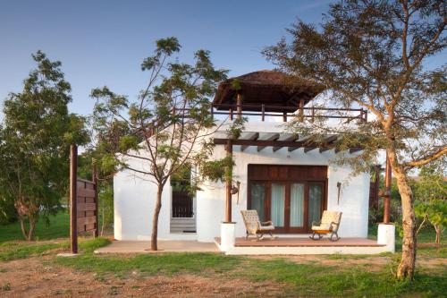 a white house with two chairs in front of it at The Serai Bandipur in Bandipūr