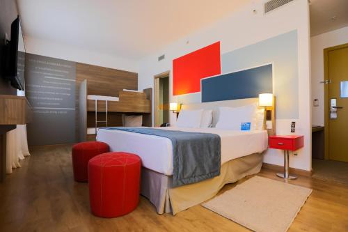 a hotel room with a large bed and red stools at TRYP By Wyndham Ribeirão Preto in Ribeirão Preto