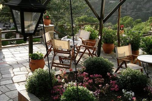 eine Terrasse mit Stühlen, einem Tisch und Blumen in der Unterkunft Hotel Petrino in Makrinítsa