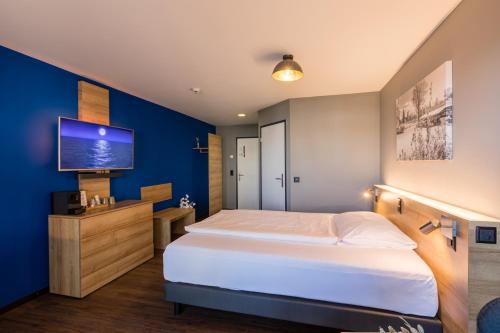 um quarto com uma cama grande e uma parede azul em Aarau West Swiss Quality Hotel em Oberentfelden