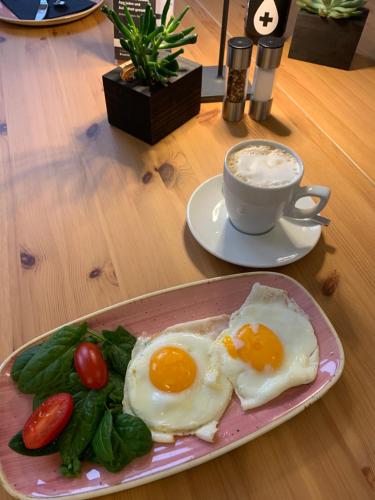 dois ovos fritos num prato rosa ao lado de uma chávena de café em Hotel Prinz Carl - Apartments mit Klimaanlage em Neckarsulm