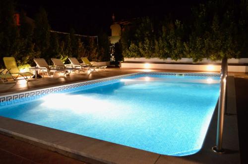 uma piscina à noite com cadeiras e luzes em Villa ELTAEL - Rita Apartment - Warm Pool from April 2025 na Manta Rota