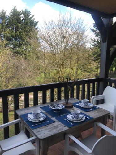 - une table en bois sur un balcon avec des assiettes et des tasses dans l'établissement le Pullman, à Deauville