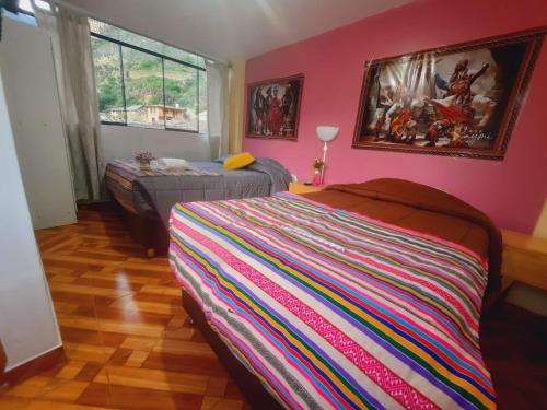 1 dormitorio con paredes rosas, 1 cama y ventana en Hostal Raymi, en Ollantaytambo