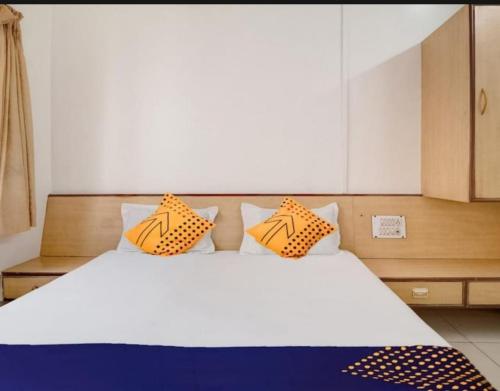 a bedroom with a large white bed with orange pillows at Hotel Rahi in Nashik