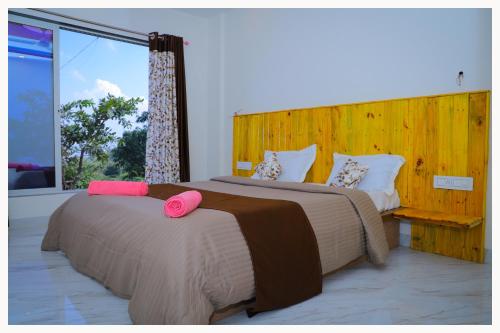 um quarto com 2 camas e uma grande janela em Sai Siddhigiri Villa em Mahabaleshwar