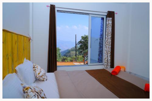 - une chambre avec un lit et une grande fenêtre dans l'établissement Sai Siddhigiri Villa, à Mahabaleshwar