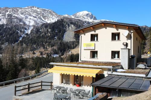 un edificio con mesas y sillas frente a una montaña en Hotel Sfazù, en Poschiavo