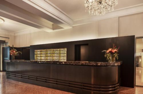 a hotel lobby with a bar and a chandelier at Eden Hotel Wolff in Munich