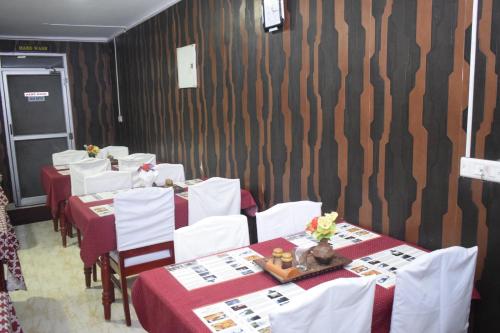 une salle à manger avec des tables et des chaises blanches dans l'établissement Hotel Apple Valley, à Kodaikānāl