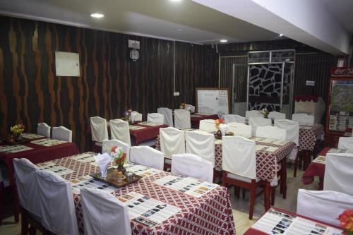 une salle à manger avec des tables et des chaises blanches dans l'établissement Hotel Apple Valley, à Kodaikānāl