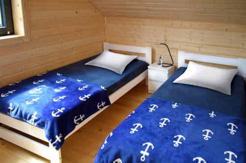 2 bedden in een kamer met blauwe lakens en witte kussens bij Nadmorskie Klimaty - Domki Całoroczne in Stegna