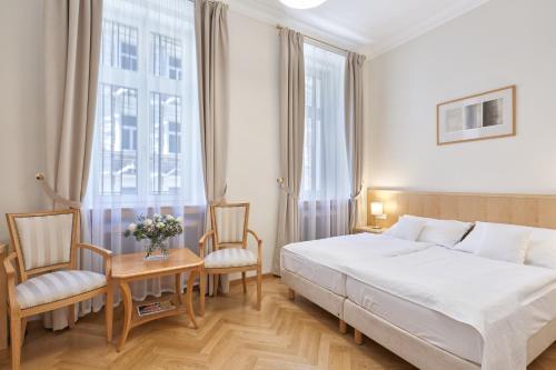 um quarto com uma cama, 2 cadeiras e uma mesa em Hotel Palatin em Karlovy Vary