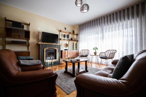 a living room with leather furniture and a fireplace at Green House - Douro in Peso da Régua