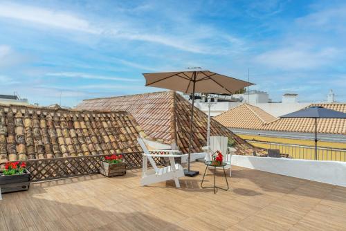 un patio avec une chaise et un parasol sur le toit dans l'établissement Main Street Apartments by Raspberry Cascade, à Faro