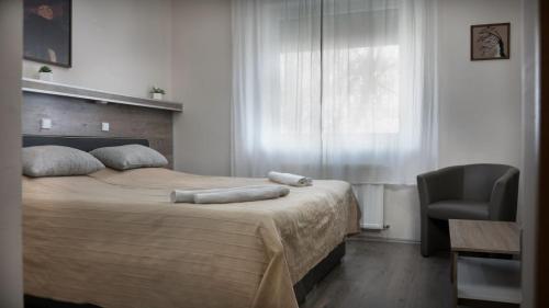 a bedroom with a bed with a chair and a window at Teke Bowling Centrum és Sport Panzió in Szeged