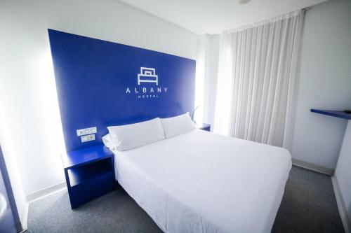 a bedroom with a white bed and a blue wall at Hostal Albany in León