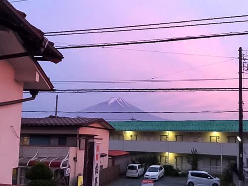 富士河口湖柏屋旅馆的一座有汽车的建筑后面的山