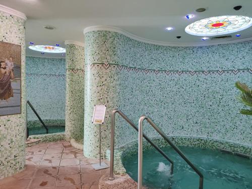 a swimming pool in a room with a tile wall at Spa Residence Carbona Apartment 105 in Hévíz