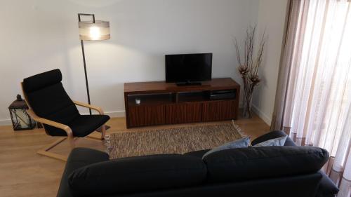 uma sala de estar com um sofá e uma cadeira e uma televisão em Vila Atlantida Apartment em Vilamoura