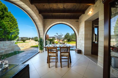 un patio al aire libre con un arco, una mesa y sillas en FOS residence - ΦΩΣ ,luxury villa, en La Canea