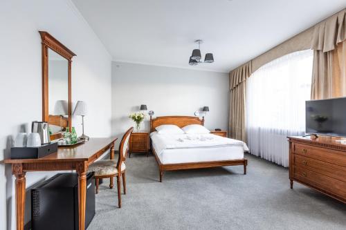 Schlafzimmer mit einem Bett, einem Schreibtisch und einem TV in der Unterkunft Hotel Pod Złotą Różą in Kielce