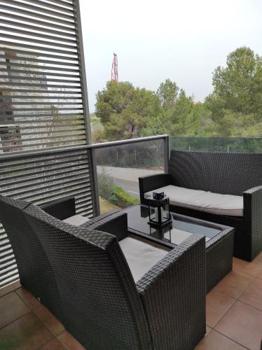 d'un balcon avec deux chaises en osier et une table. dans l'établissement Paradise Village Port Aventuras, à Salou