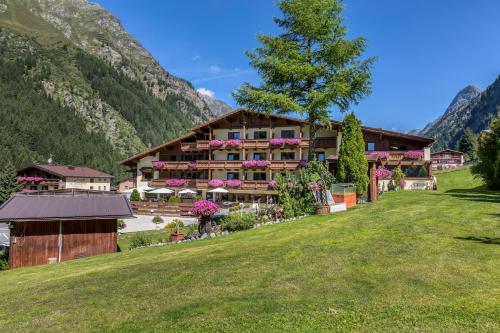 hotel w górach z zielonym trawnikiem w obiekcie Hotel Sonnblick w mieście St. Leonhard im Pitztal