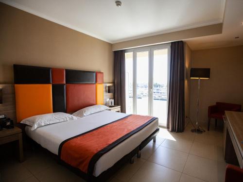 um quarto com uma cama grande e uma janela grande em Hotel Tiber em Fiumicino