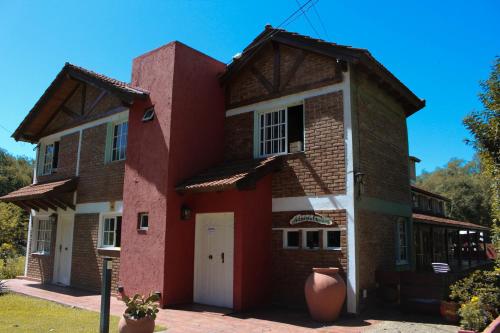 una casa de ladrillo rojo con puerta blanca en La Palapa ApartHotel, en Villa General Belgrano