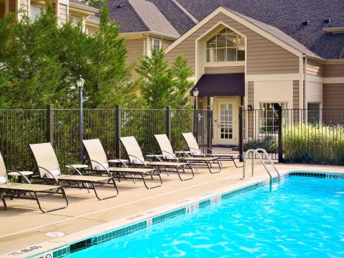 a swimming pool with lounge chairs next to a house at Sonesta ES Suites Chicago - Schaumburg in Schaumburg