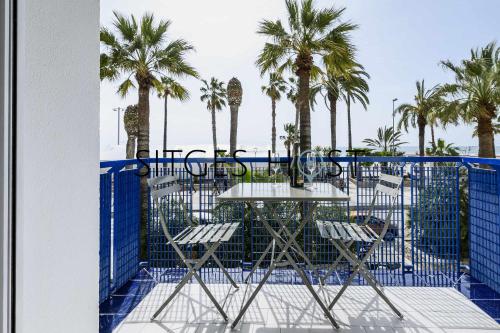 a table and chairs on a balcony with palm trees at A 20 metros de la playa in Sitges