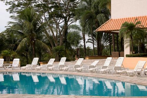 uma fila de espreguiçadeiras brancas junto a uma piscina em Hotel Michelangelo em Sao Jose do Rio Preto