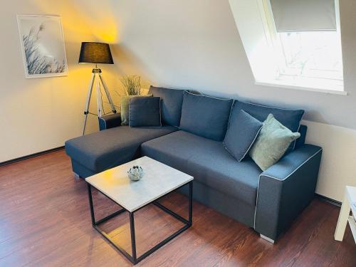 a living room with a blue couch and a table at Exclusives Apartment im Herzen von Westerland in Westerland (Sylt)