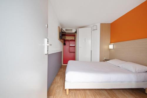 um quarto com uma cama branca e uma porta vermelha em Premiere Classe Lyon Est - Bron Eurexpo em Décines-Charpieu