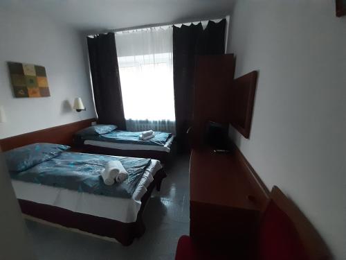 um pequeno quarto com 2 camas e uma janela em OŚRODEK WYPOCZYNKOWY MAZOWSZE W KARPACZ em Karpacz