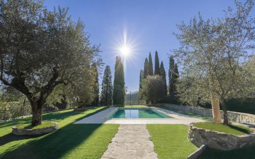 a pool in a garden with trees and the sun in the background at Rivo della Corte in Pistoia